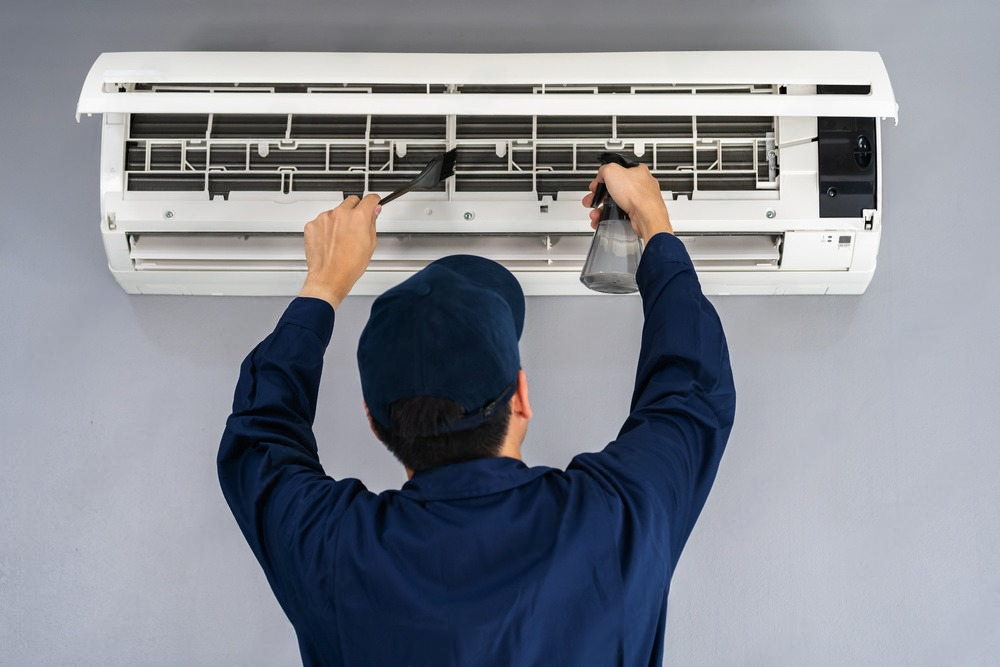 a man is cleaning an air conditioner with a brush .