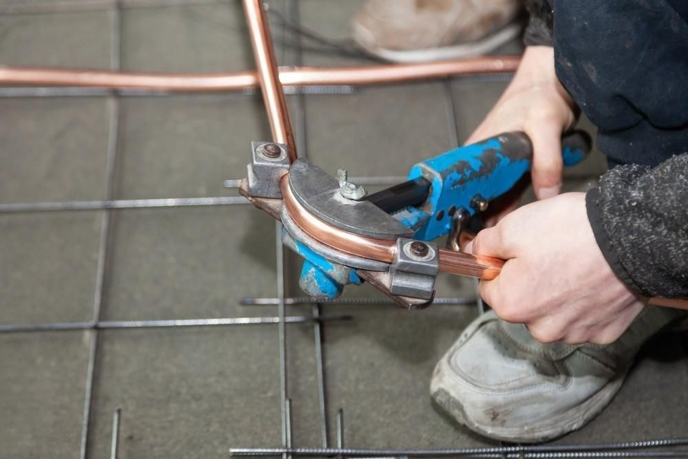 a person is using a pipe bending machine to bend copper pipes .