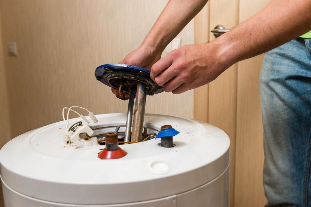 a man is fixing a water heater in a bathroom .