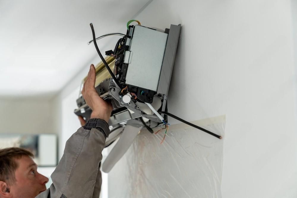 a man is installing an air conditioner on a wall .
