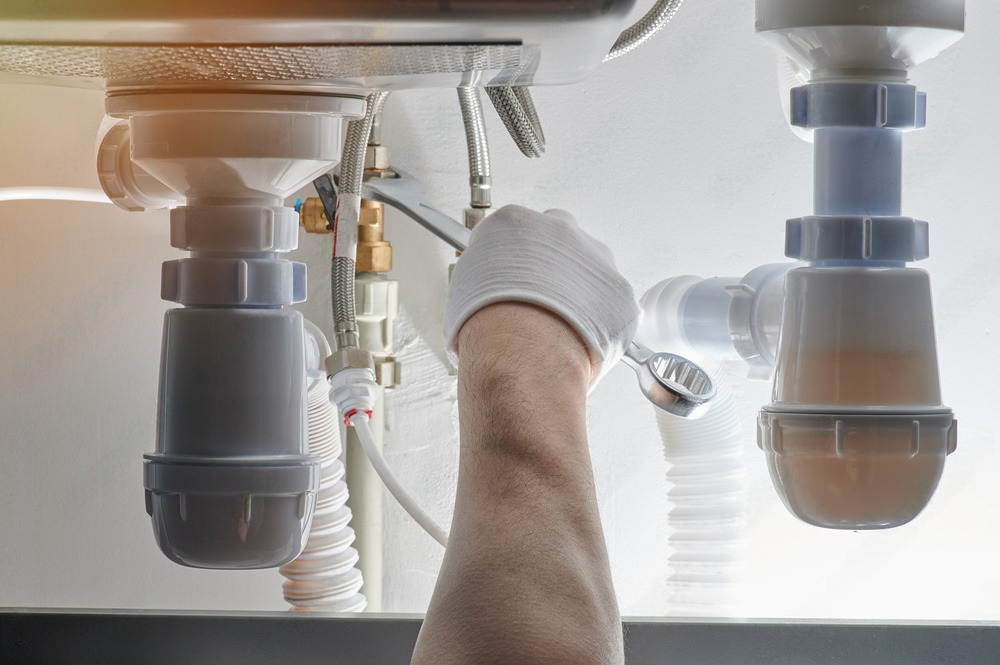 a plumber is fixing a sink with a wrench .
