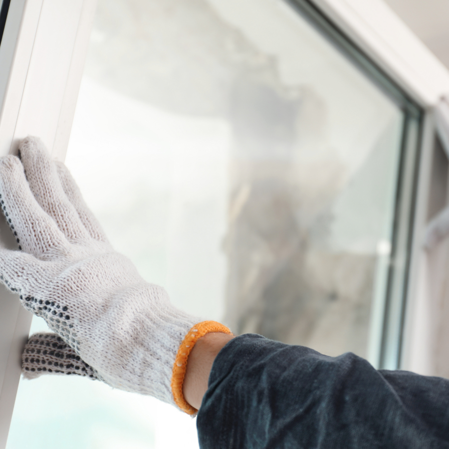 A person wearing gloves is repairing a window.