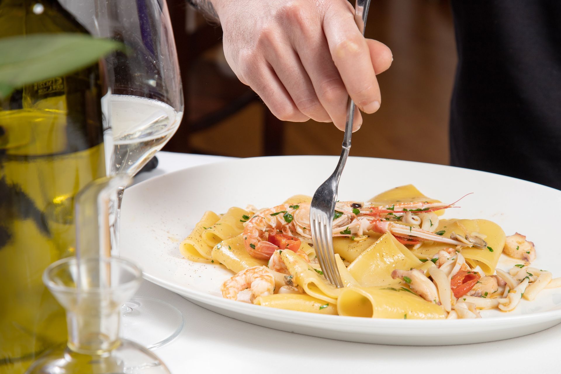 A person is cutting a plate of pasta with a fork.