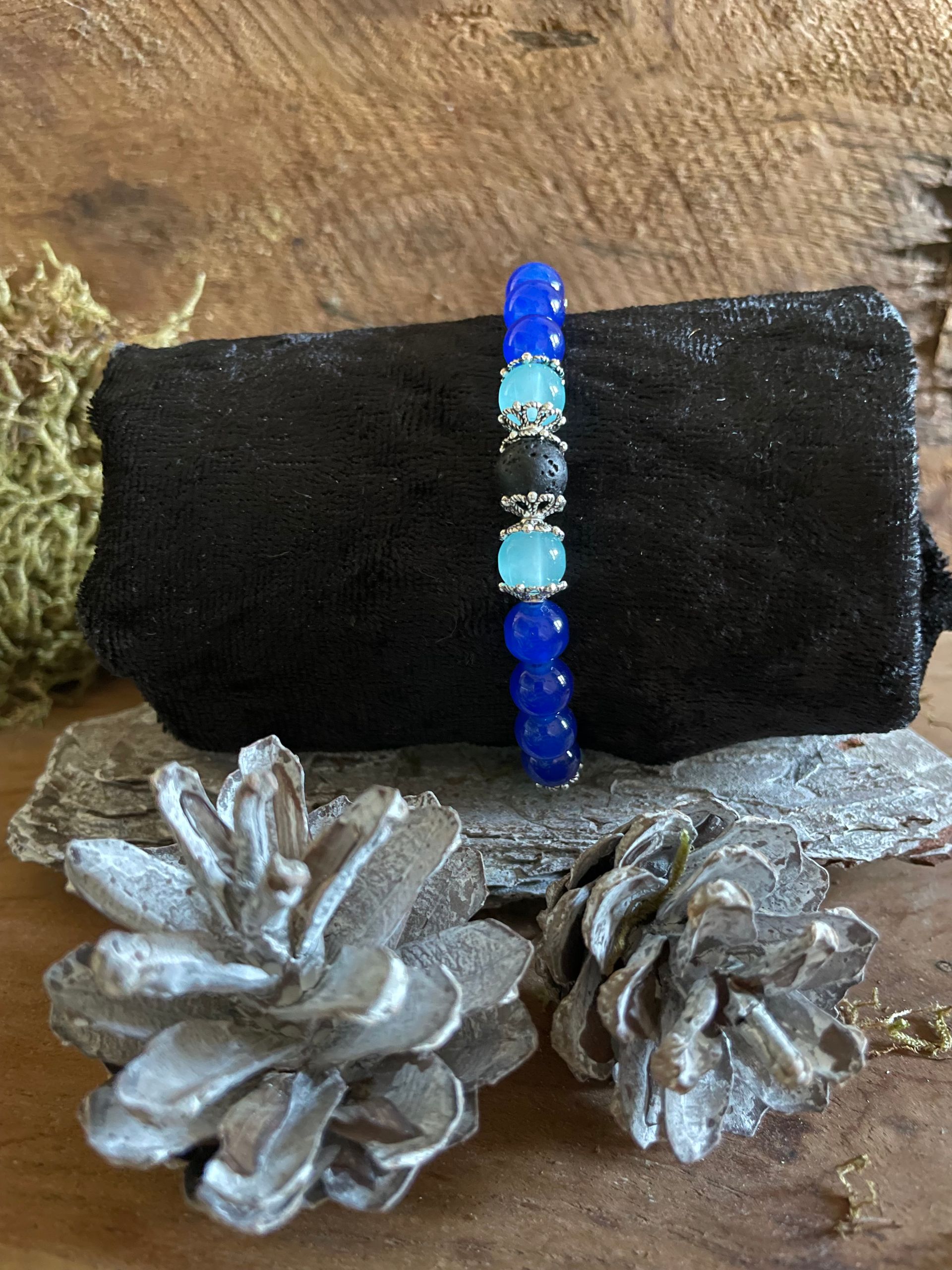 Armband met blauwe, turquoise en zwarte kralen op een zwarte fluwelen achtergrond.