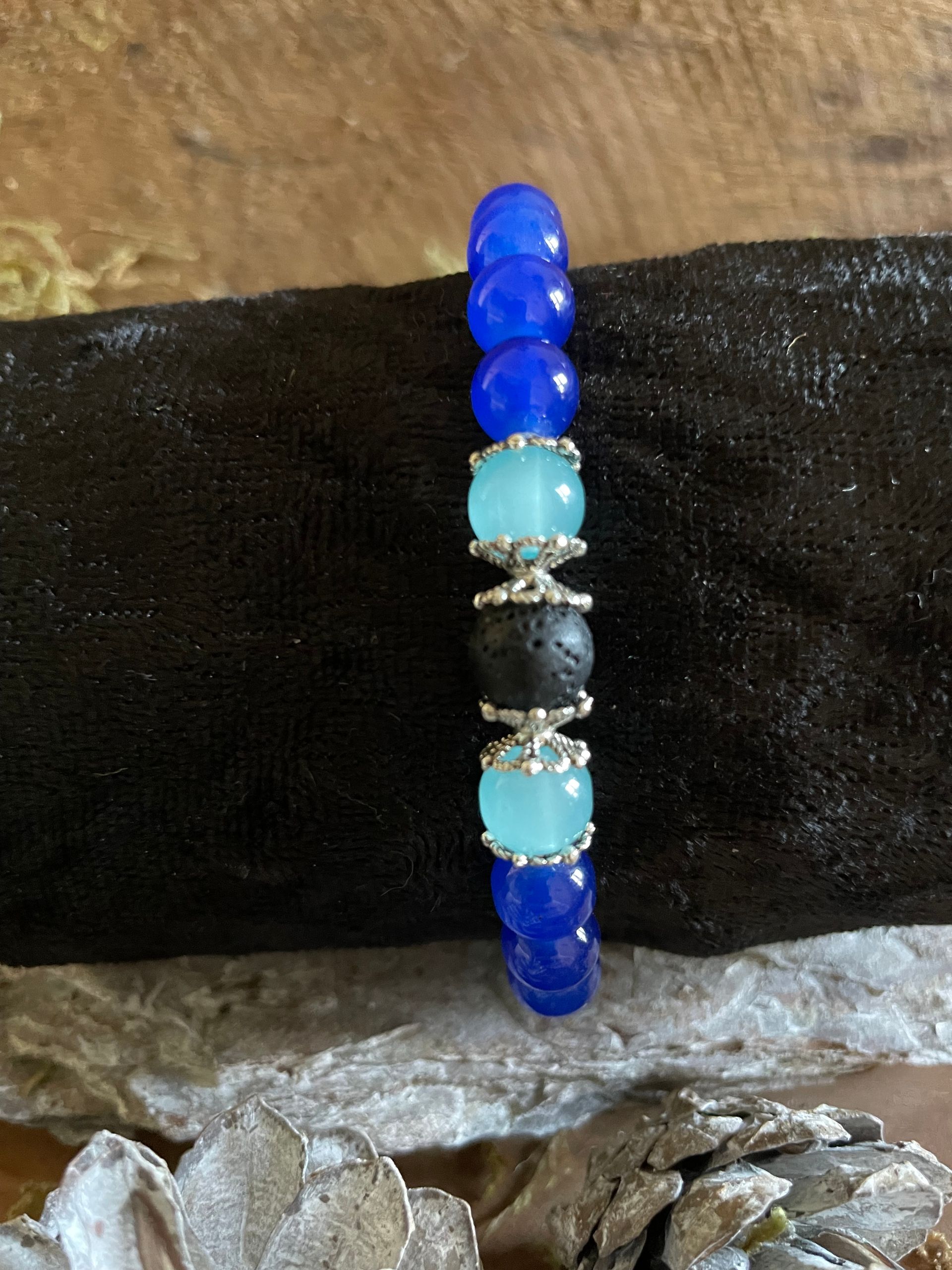 Armband met blauwe, turquoise en zwarte kralen op een zwarte fluwelen achtergrond.