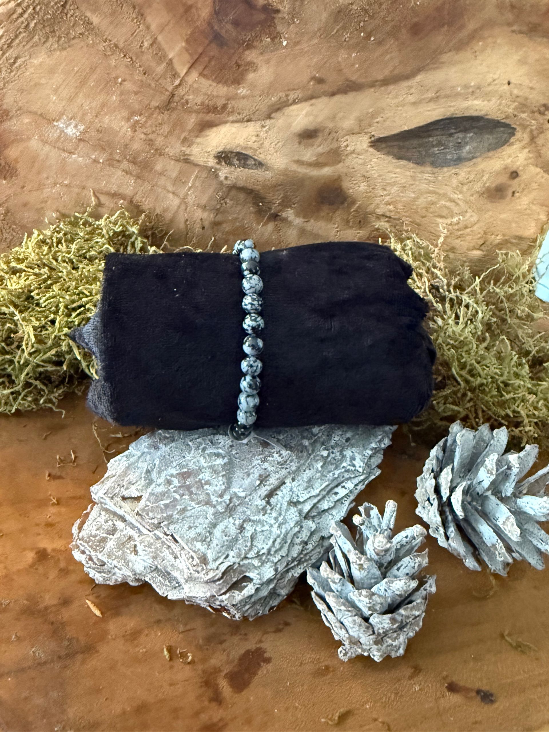 Armband van zwart-wit gespikkelde stenen kralen op een zwarte fluwelen doek.