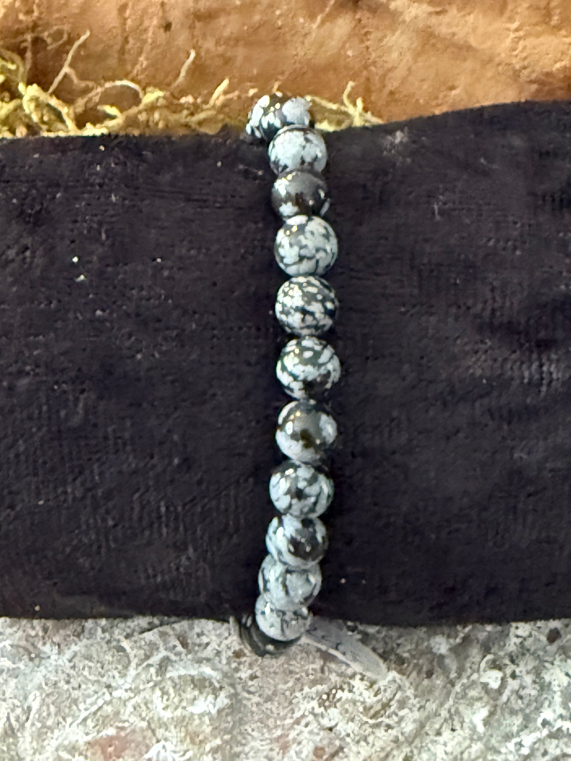 Armband van zwart-wit gespikkelde stenen kralen op een zwarte fluwelen doek.