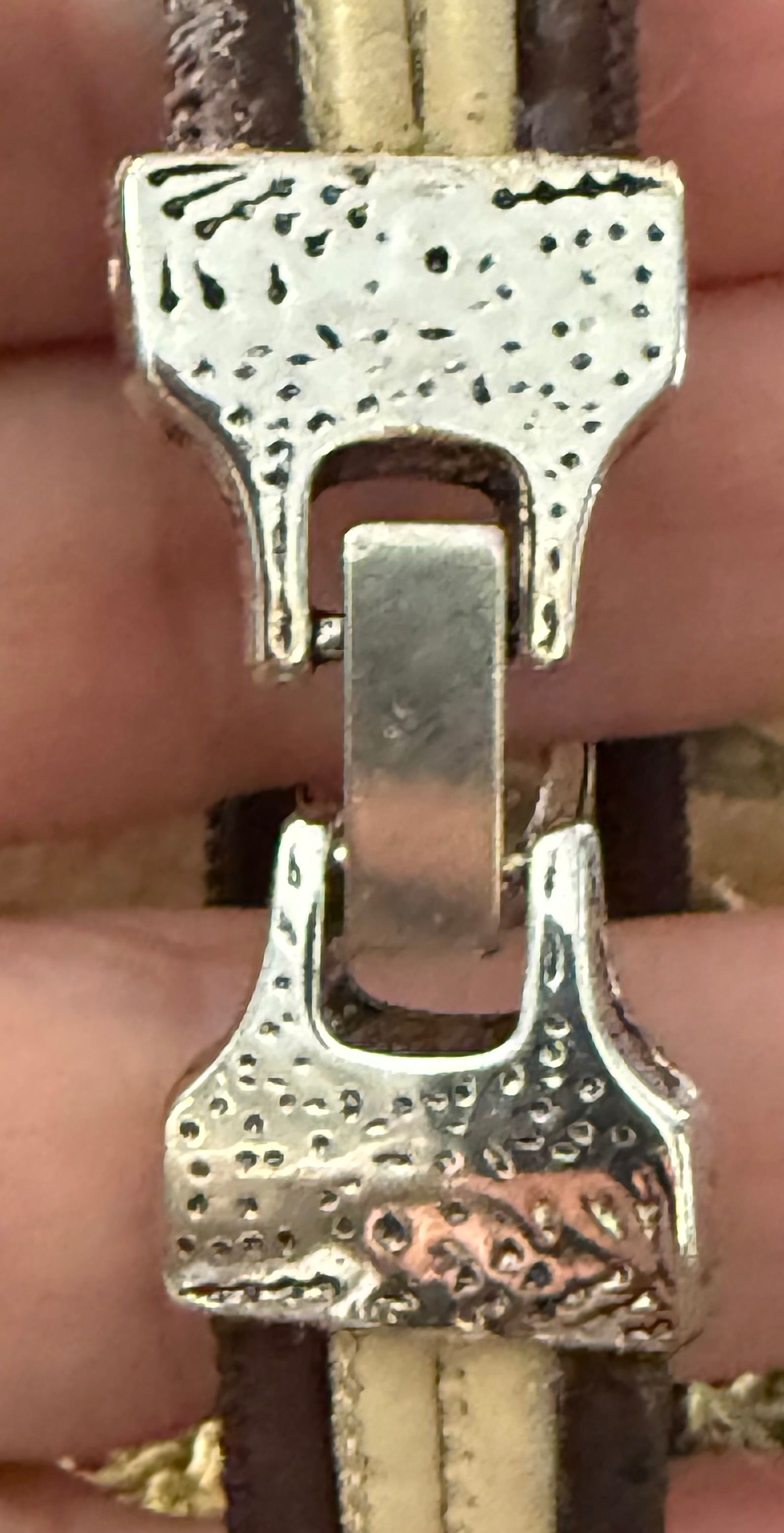 Bruine leren armband met een zilveren oneindigheidssymbool en crèmekleurige knopen.