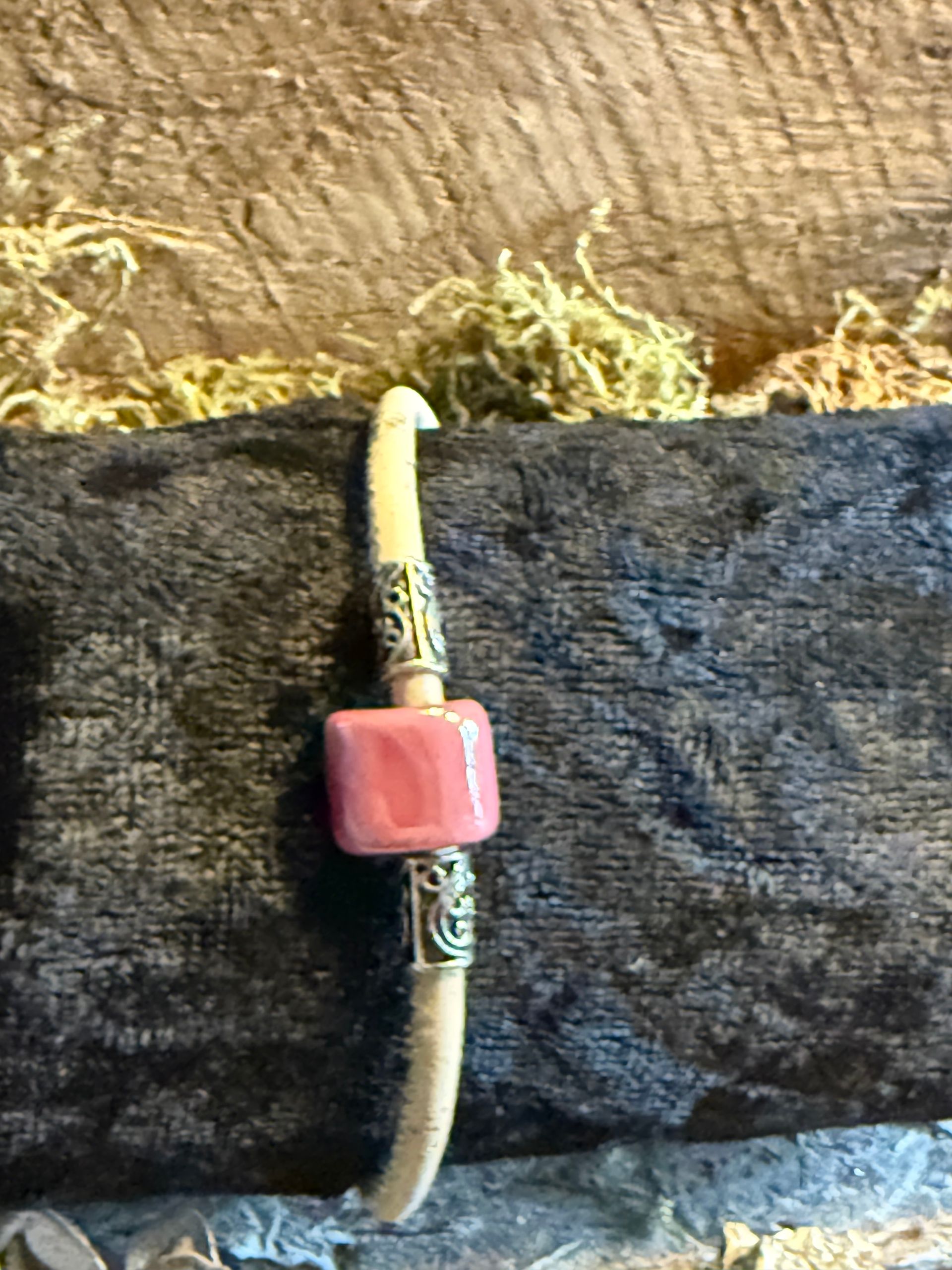 Armband met roze vierkante kraaltjes en zilveren accenten op een lichtbruine band.