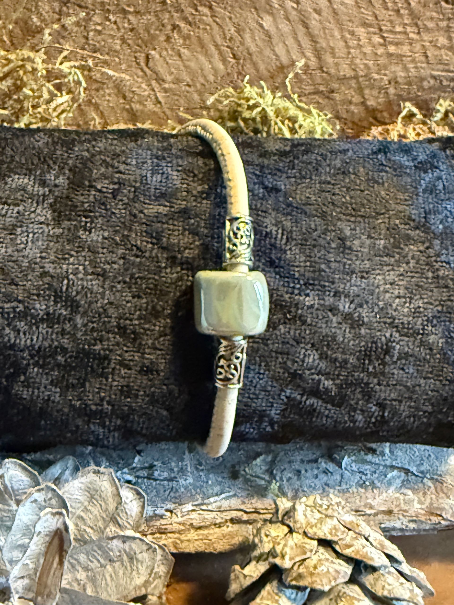 Drie kleurrijke kralenarmbanden op een zwarte display met een mosachtige achtergrond.