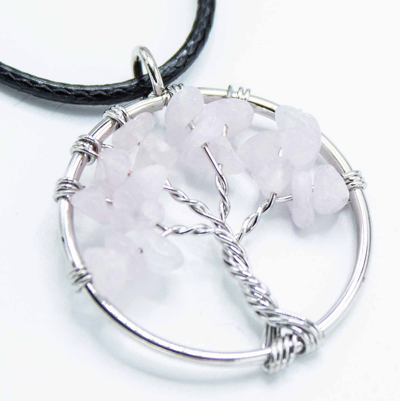 Zilveren draadhanger in de vorm van een boom met roze steentjes aan een zwart koord.