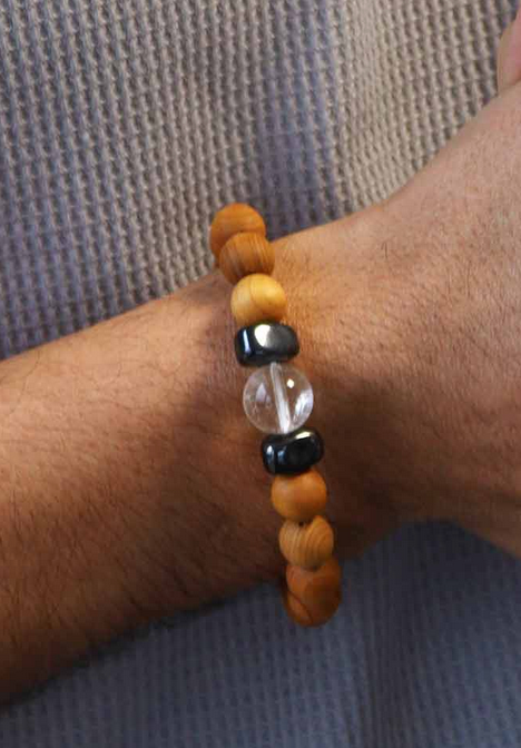 Pols met een armband van houten en stenen kralen.