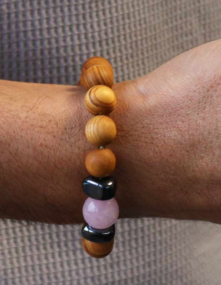 Close-up van de pols van een persoon die een kralenarmband draagt ​​met houten en edelstenen kralen.