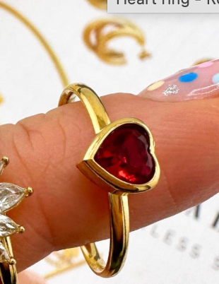 Goudkleurige ring met een rode hartvormige edelsteen.
