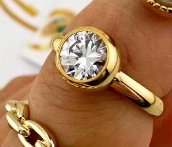 Verguld roestvrijstalen ring met een grote, transparante edelsteen in een chatonzetting.