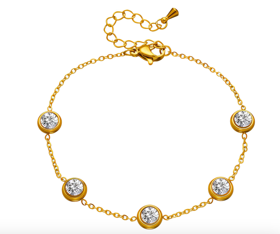 Gouden armband met vijf ronde, transparante stenen op een mosachtige ondergrond.