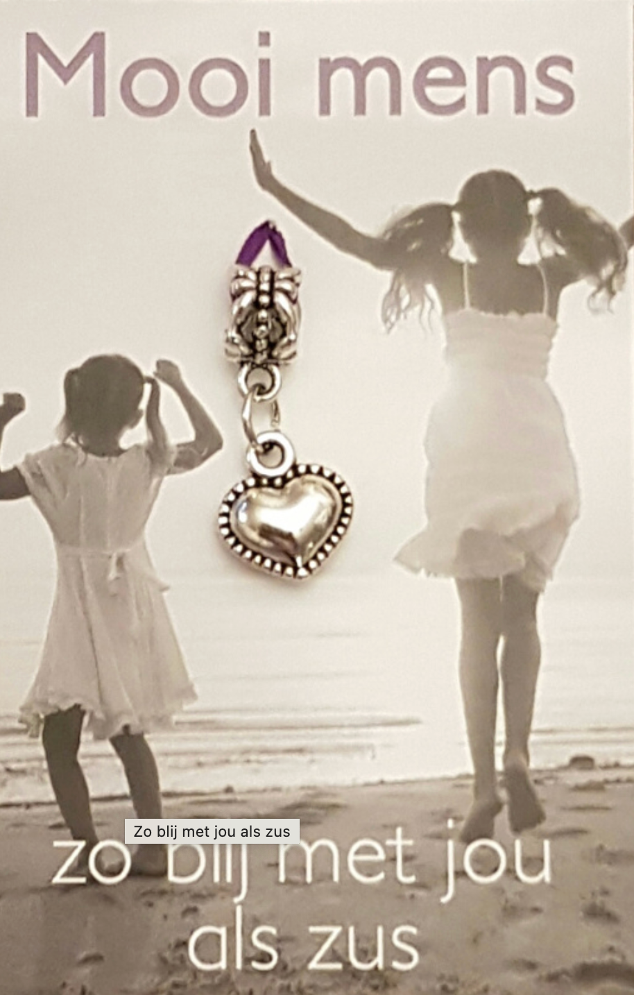 Two girls on beach, one jumping. Charm with heart and text: 