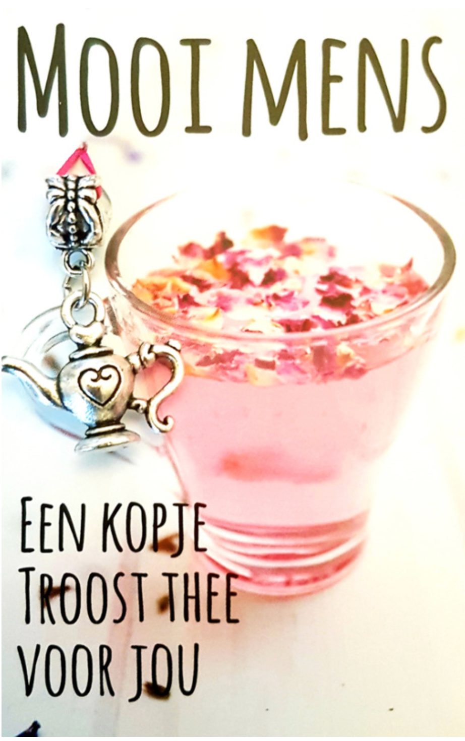 Pink tea in a clear glass with flower petals, next to a  teapot charm.  