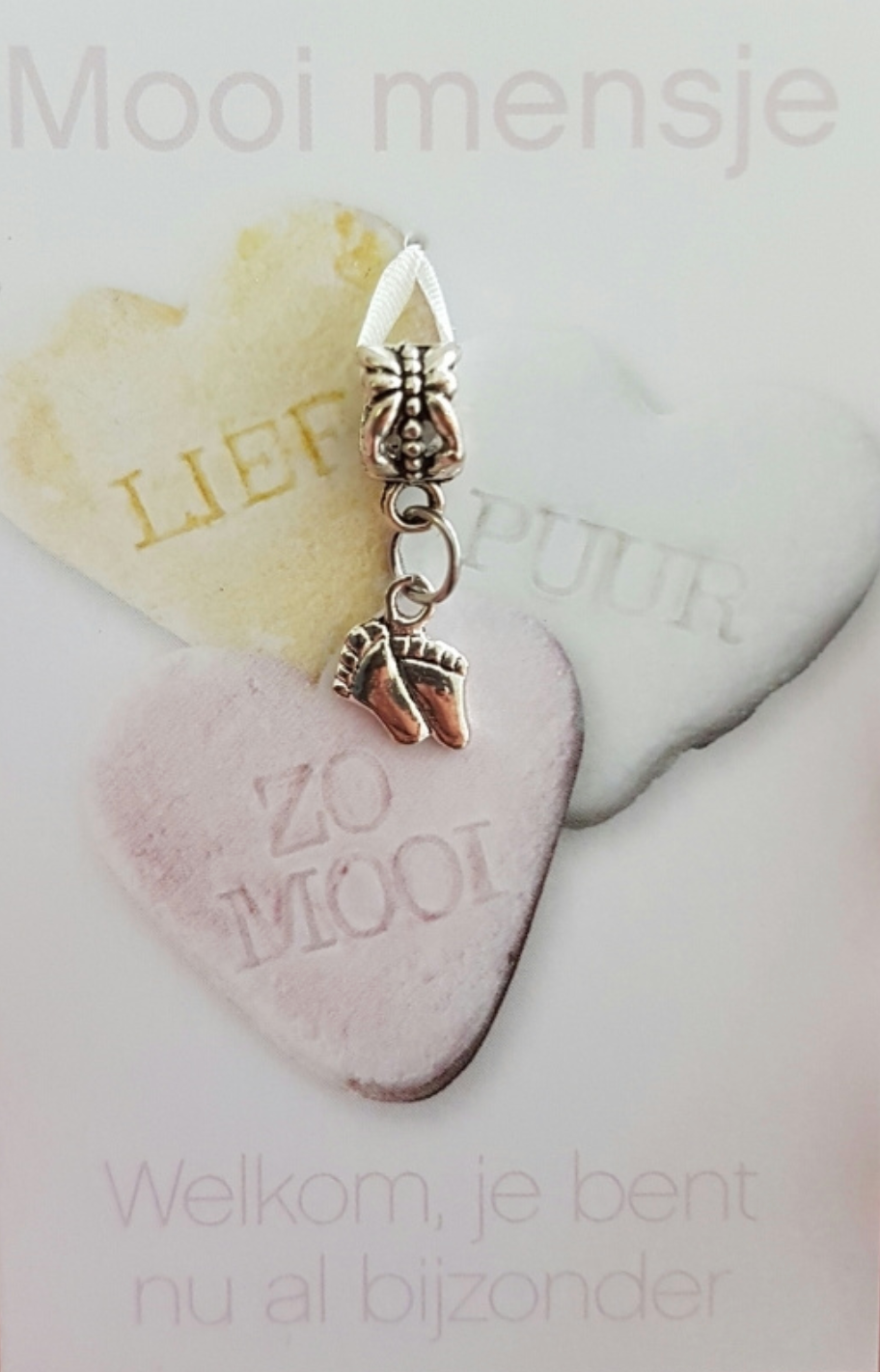 Silver charm with tiny feet dangling over two heart-shaped candies. Mooi mensje,