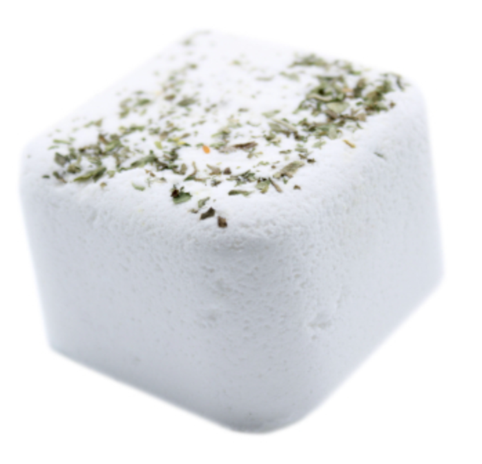 Wit vierkant dessert bestrooid met groene kruiden op een bedje van groene kruimels.