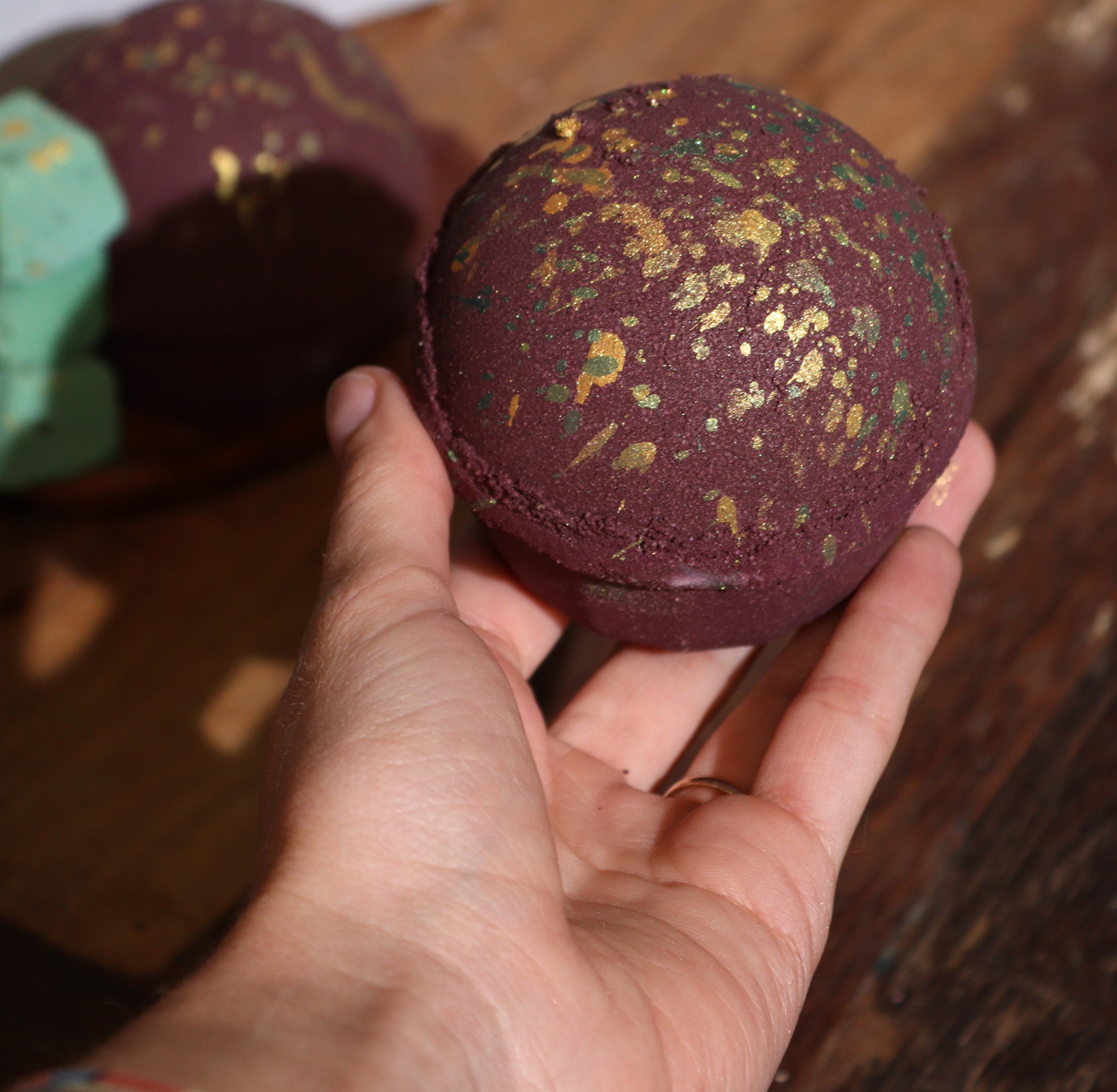 Donkerbruine bruisbal met gouden en groene glitters, staand op een donkere ondergrond.