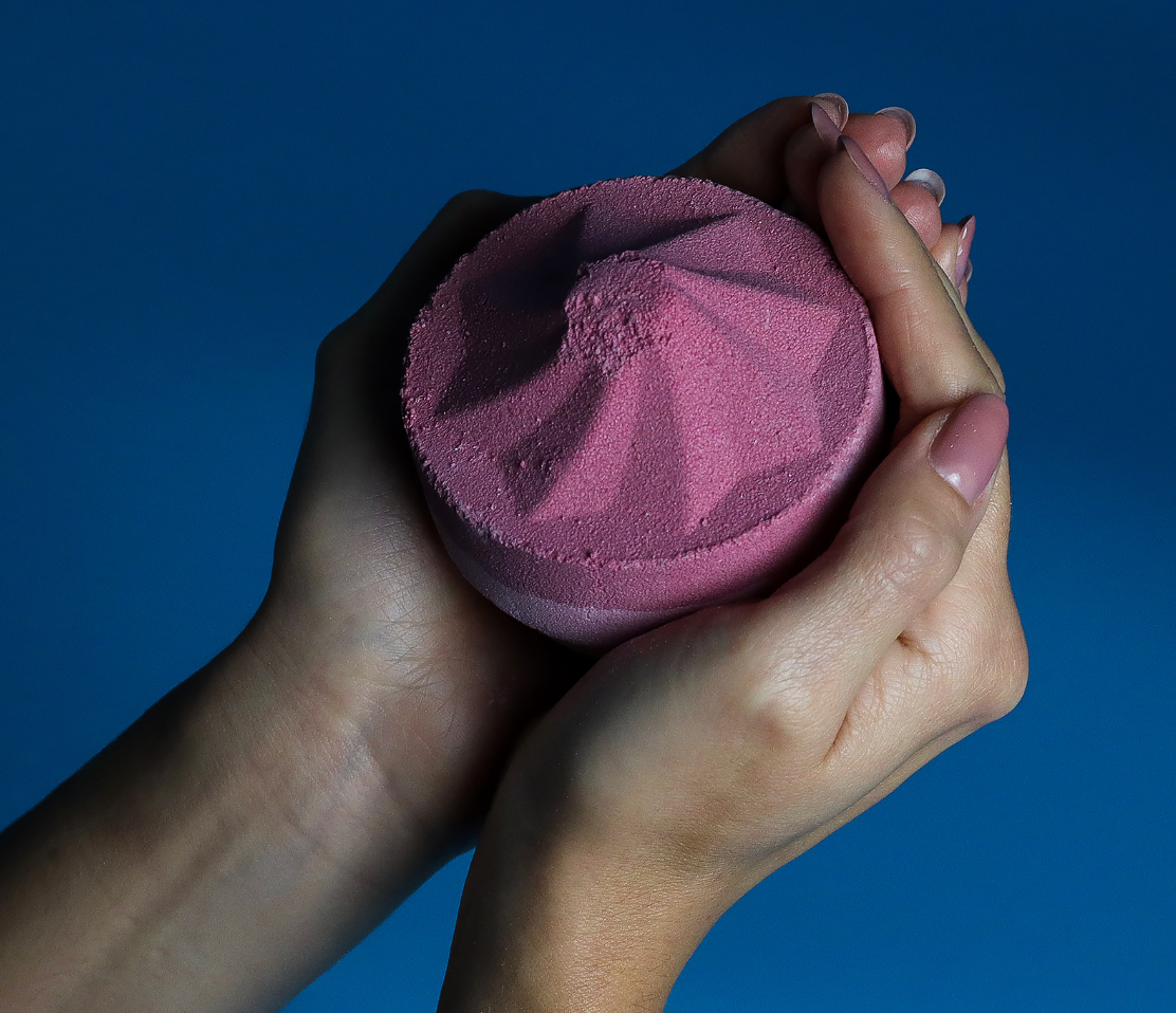 Rode, gelaagde bruisbal op een turquoise achtergrond; het bovenste gedeelte heeft de vorm van een berg.