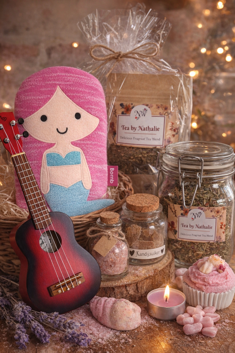 Cadeaupakket met zeemeerminthema, inclusief ukelele, pop, thee, badproducten, kaars en cupcake. Zachte, warme verlichting.