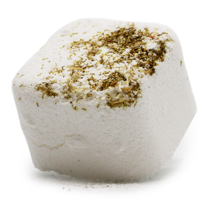 Witte bruisbal voor in bad met gedroogde kruiden, handdoek, kaars en bloemen.