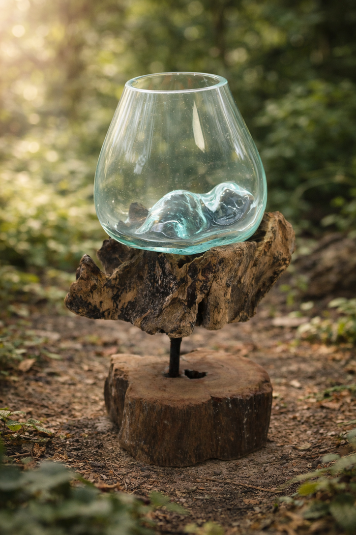 Glazen schaal met blauwe objecten, op een houten voet, in een buitenomgeving.