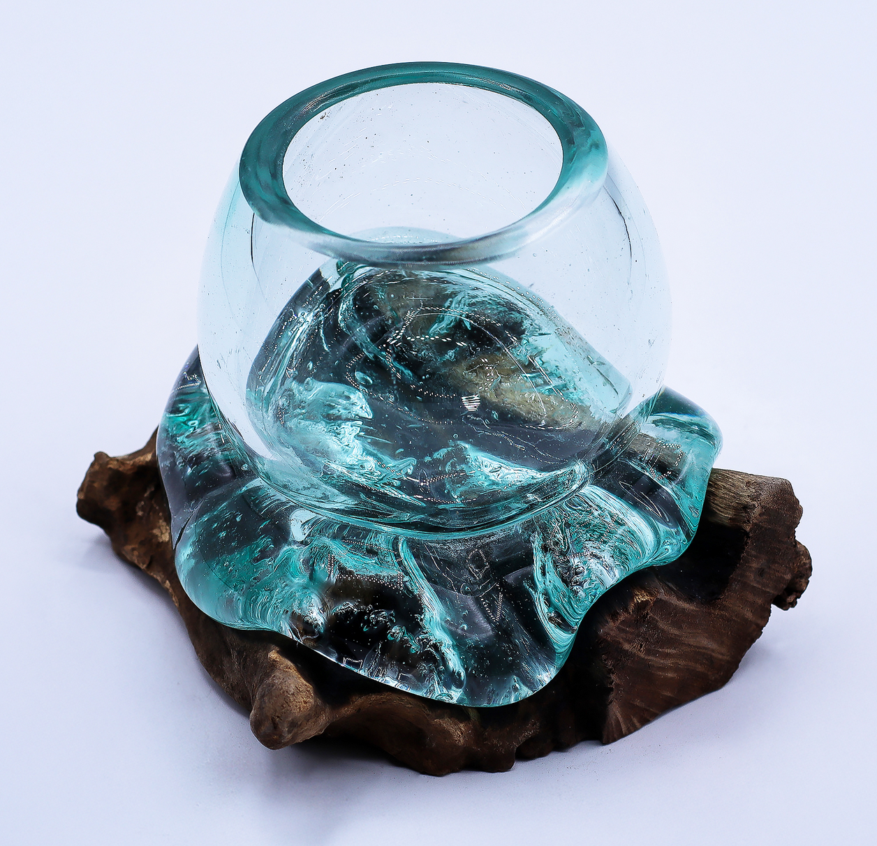 Een sculptuur van een glazen kom op een rotsachtige sokkel, die buiten in een bos is geplaatst.