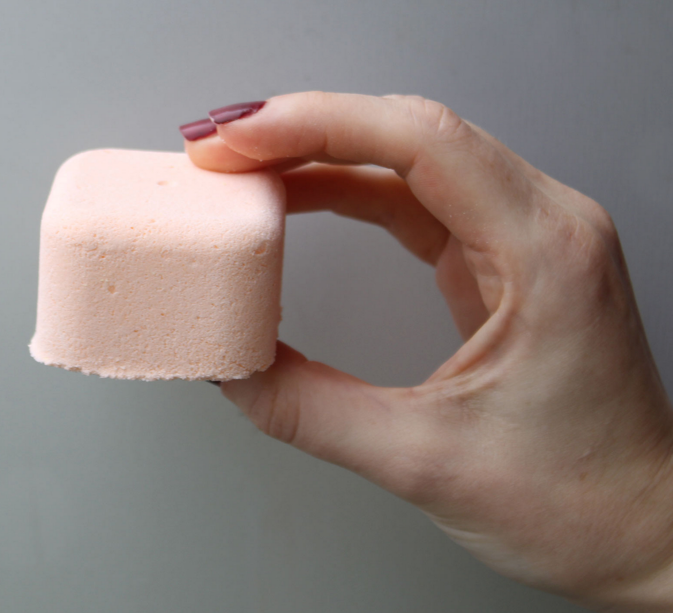 Twee lichtroze, vierkante bruisballen op een bedje van groen mos.