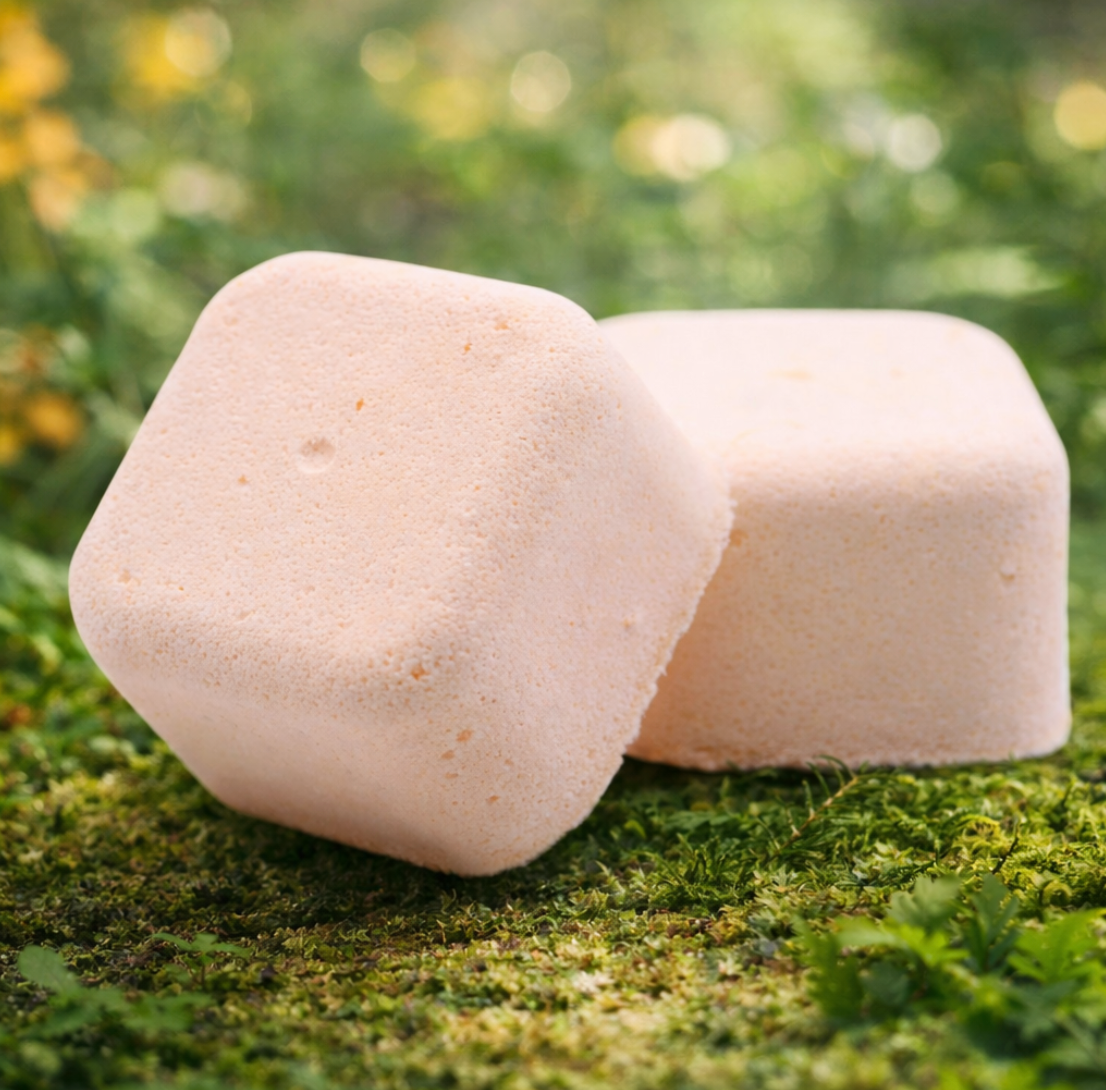 Twee lichtroze, vierkante bruisballen op een bedje van groen mos.