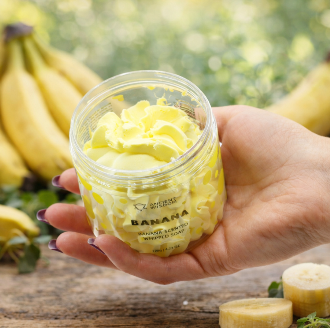 Een hand houdt een pot gele, luchtige lichaamszeep vast met het opschrift 