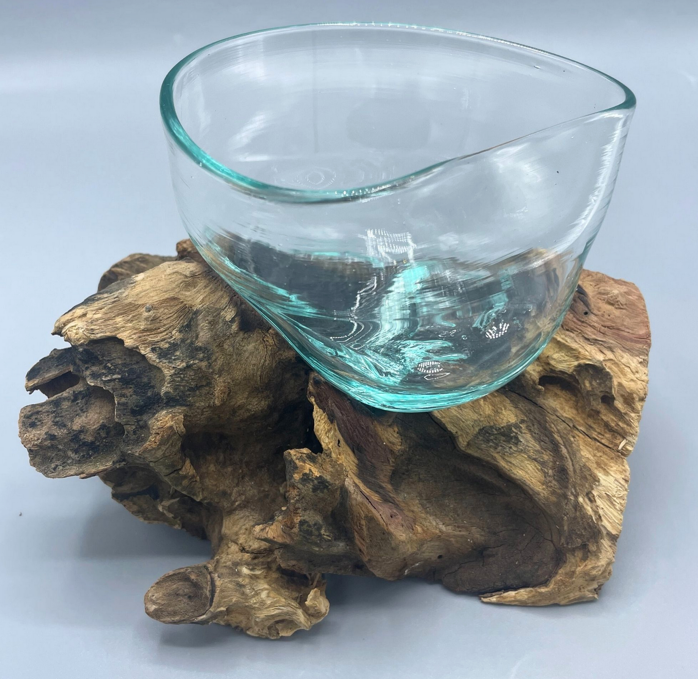 Doorzichtige glazen schaal met golvende rand, rustend op een bruine houten voet, geschikt voor buitengebruik.