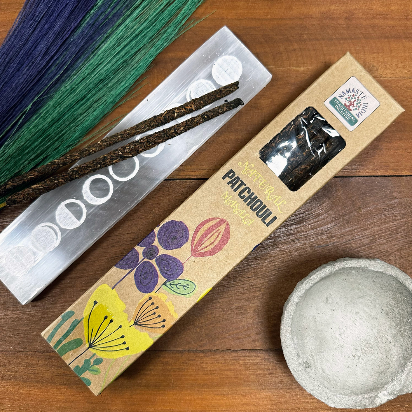 Doosje patchouli wierookstokjes, seleniet houder, decoratieve schaal, gedroogd gras op hout.