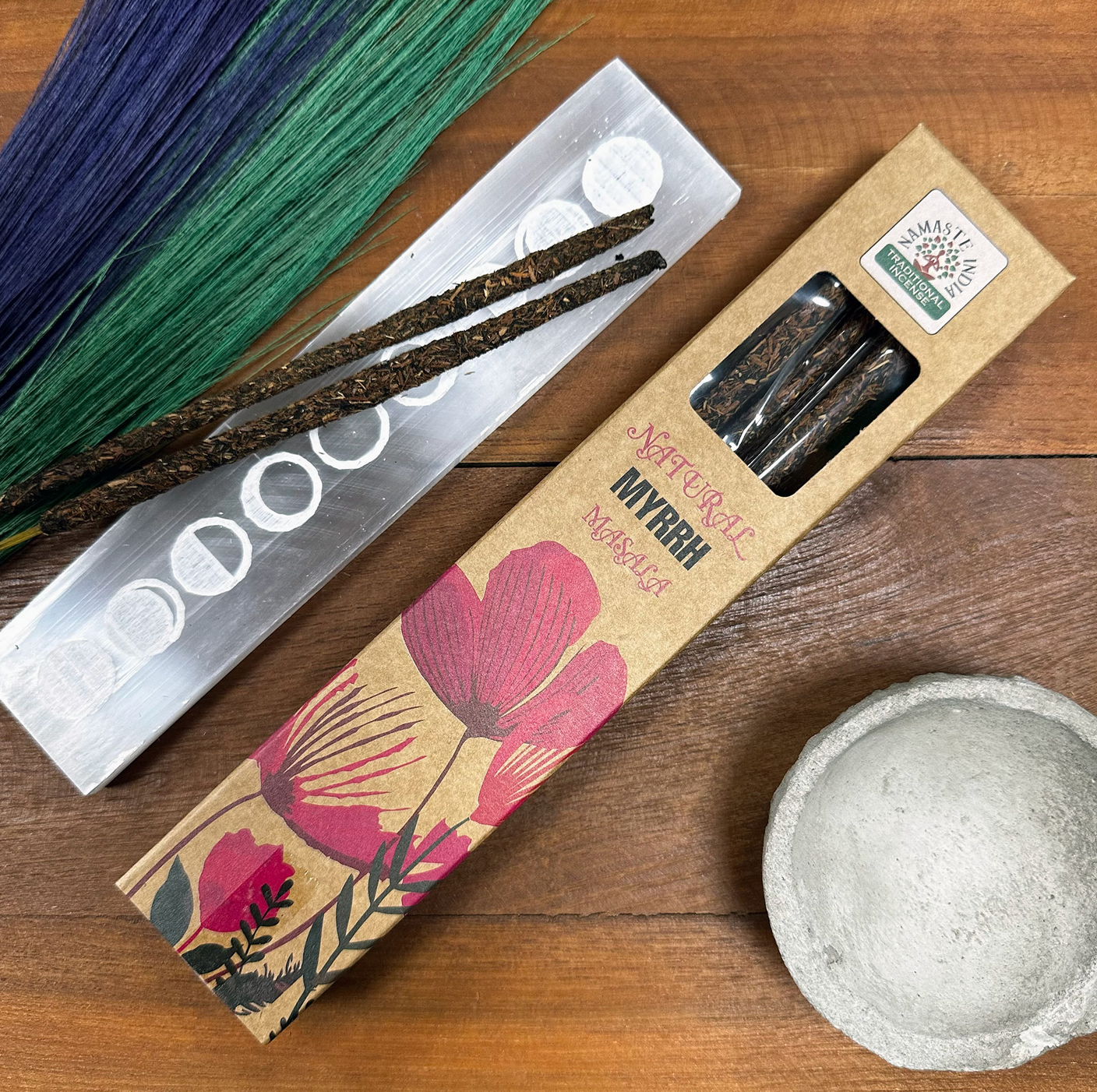 Wierookstokjes, een brander, een houder en een bloemendoos op een houten tafel.