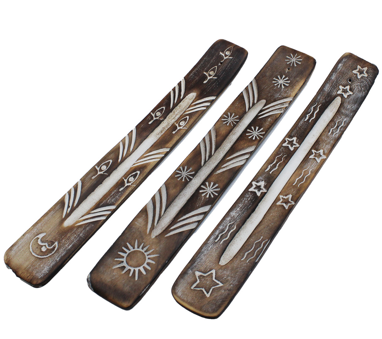 Drie gebeeldhouwde houten wierookhouders met sterren, manen en symbolen op een houten tafel met kristallen en kaarsen.
