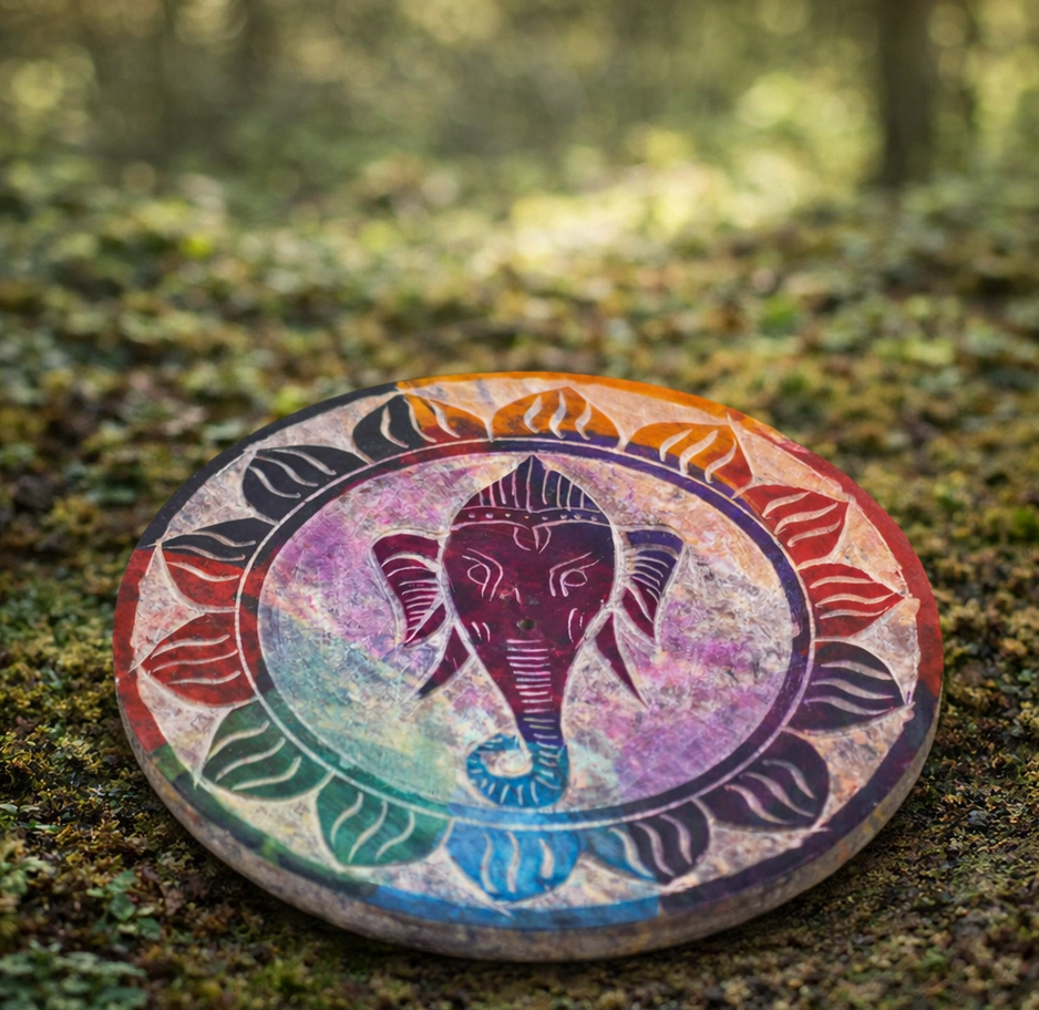 Een ronde onderzetter met een afbeelding van Ganesha in een kleurrijke, bloemachtige mandala op een met bedekte ondergrond.