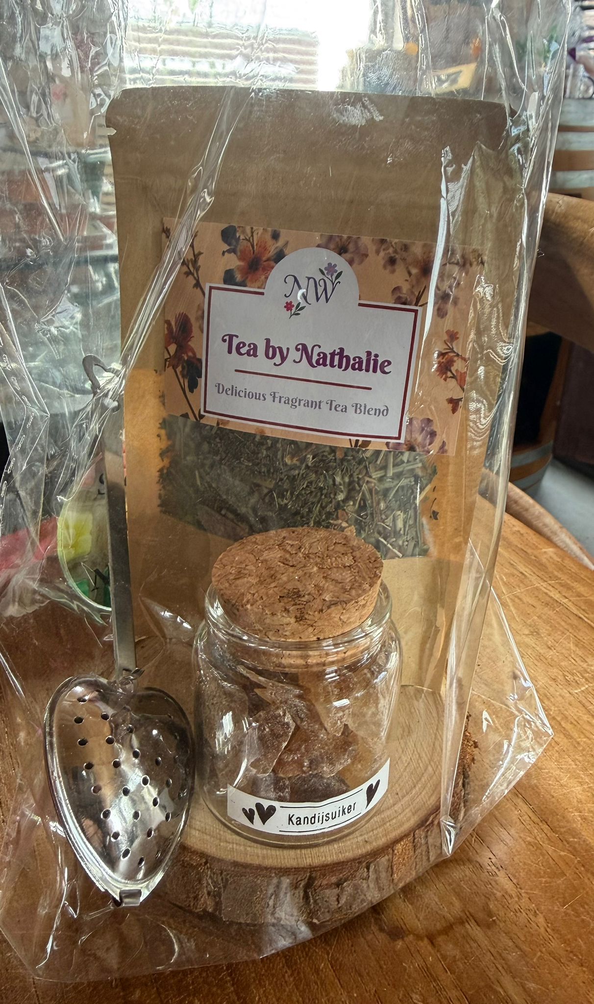 Cadeauset met thee: zakje losse thee, pot met kurken deksel, theelepel, op een houten schijfje.