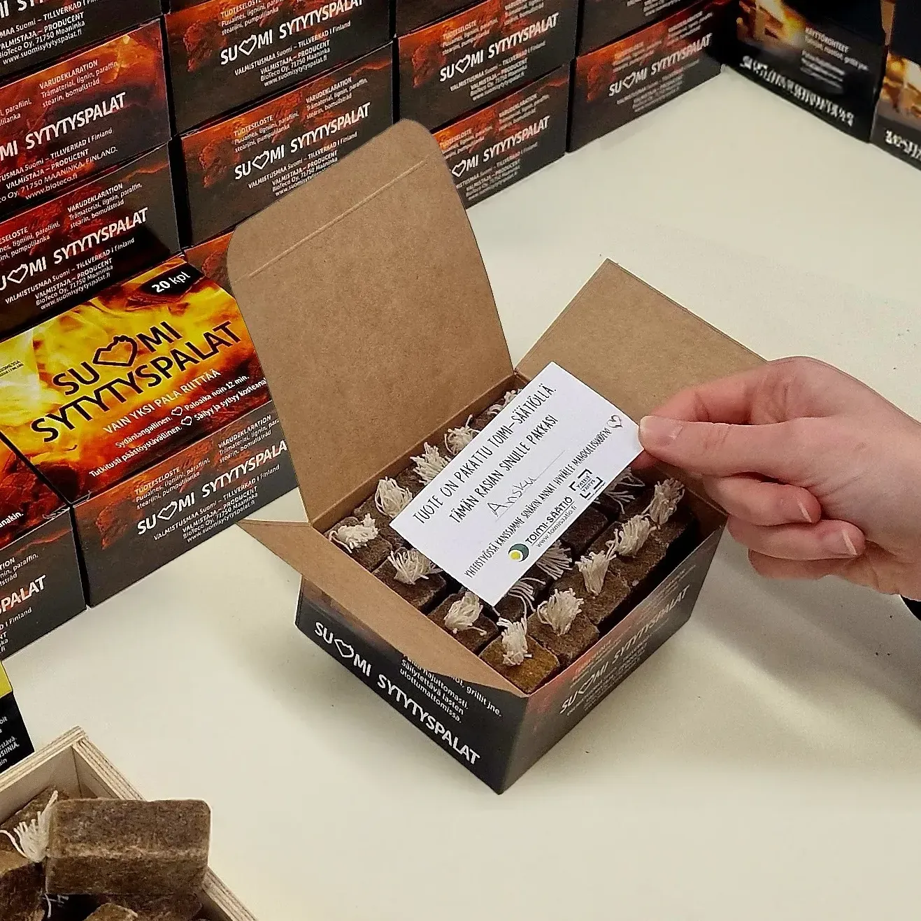 A person is opening a box of Suomi Sytytyspalat