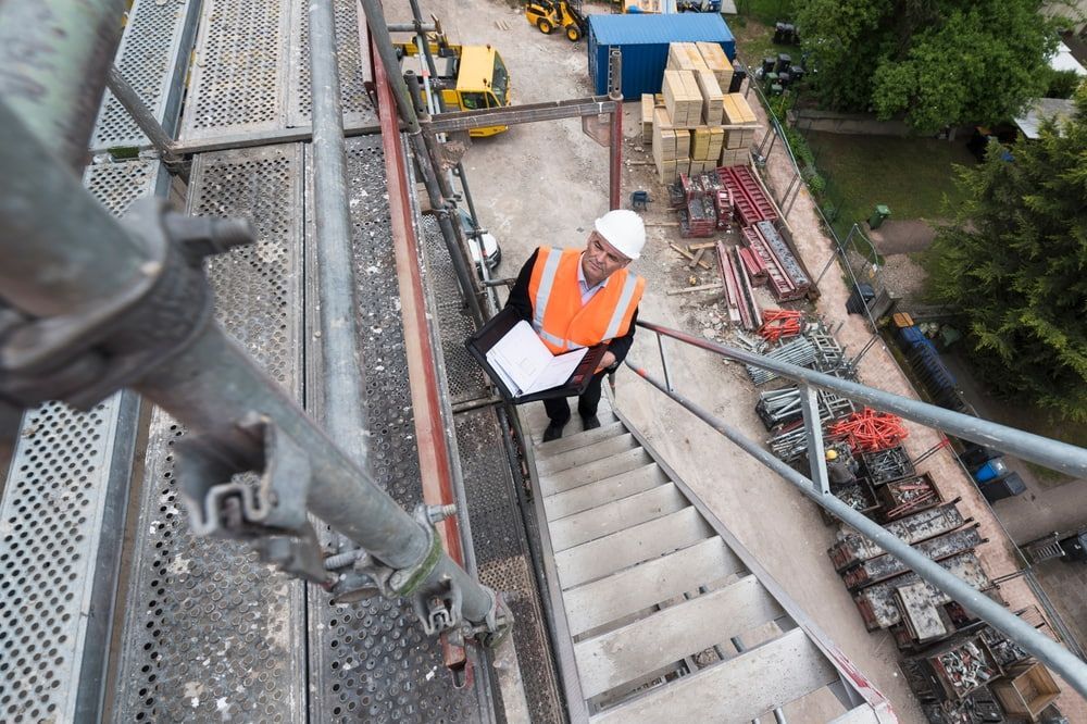 A Man Is Standing On Top Of A Set Of Stairs At A Construction Site — Fahlstrom Scaffolding Cairns Pty Ltd in Gordonvale, QLD