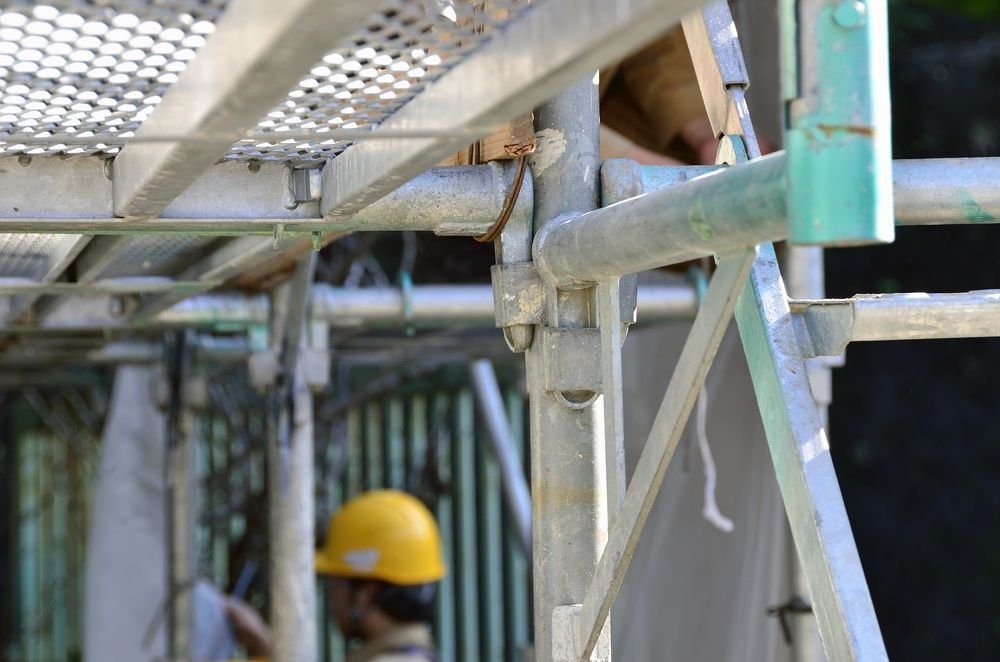 A Man Wearing A Hard Hat Is Standing On A Scaffolding — Fahlstrom Scaffolding Cairns Pty Ltd in Gordonvale, QLD