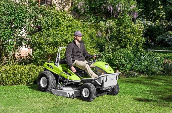 A Red Lawn Mower is Mowing a Lush Green Field — Stockers & Partridge In Raymond Terrace, NSW