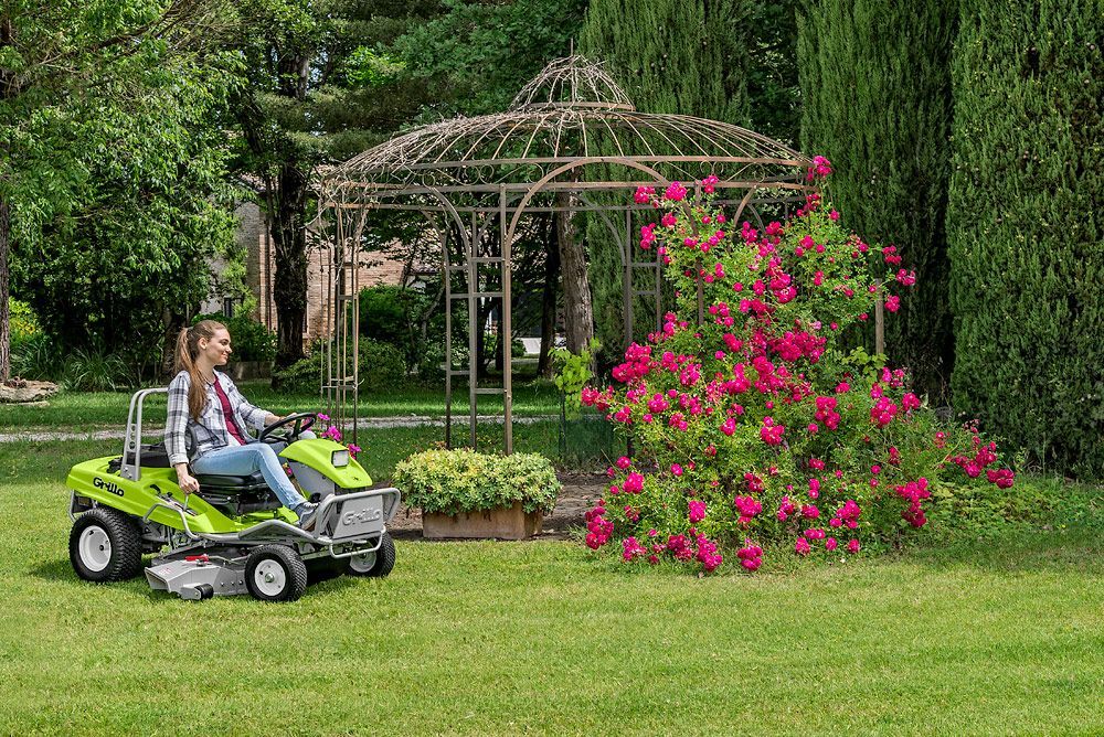 A Woman is Riding a Lawn Mower on a Lush Green Lawn — Stockers & Partridge In Paterson, NSW