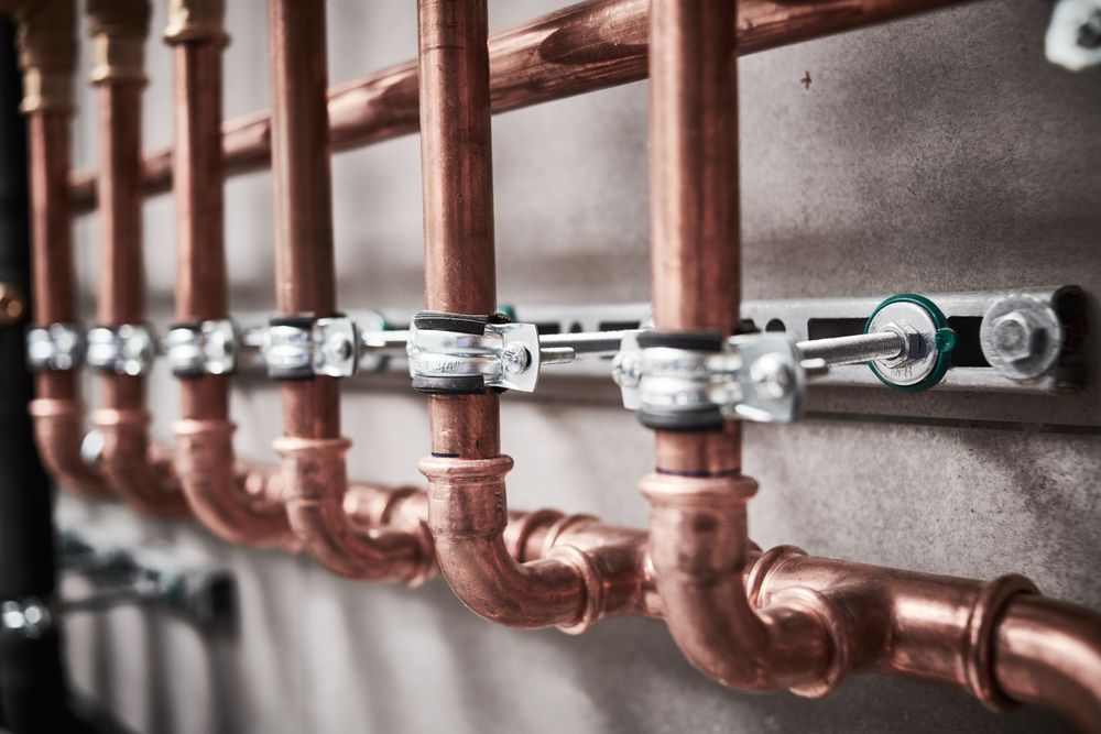 A Row of Copper Pipes Hanging on a Wall — Stockers & Partridge In Dungog, NSW
