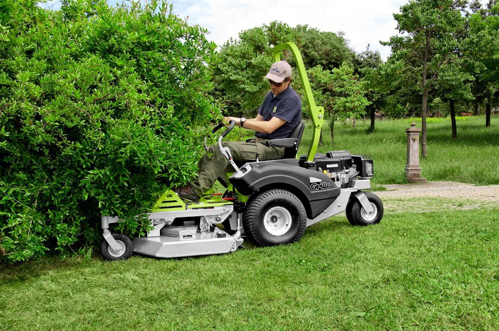 A Red Lawn Mower is Parked in a Lush Green Field — Stockers & Partridge In Paterson, NSW