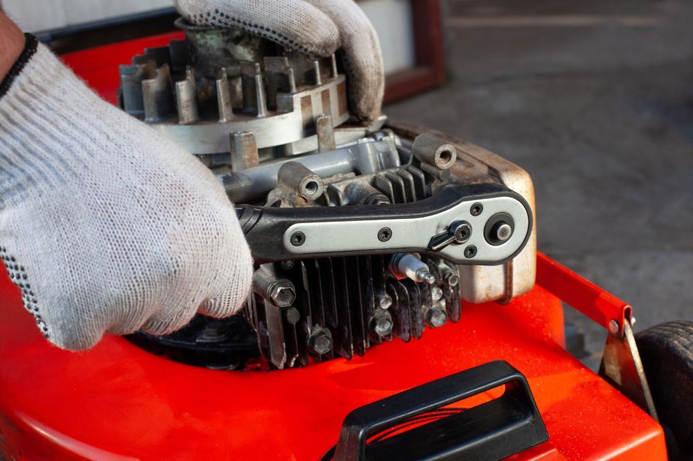 A Person is Fixing a Lawn Mower With a Wrench — Stockers & Partridge In Paterson, NSW