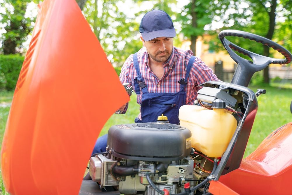 A Man is Working on a Lawn Mower With the Hood Open — Stockers & Partridge In Paterson, NSW