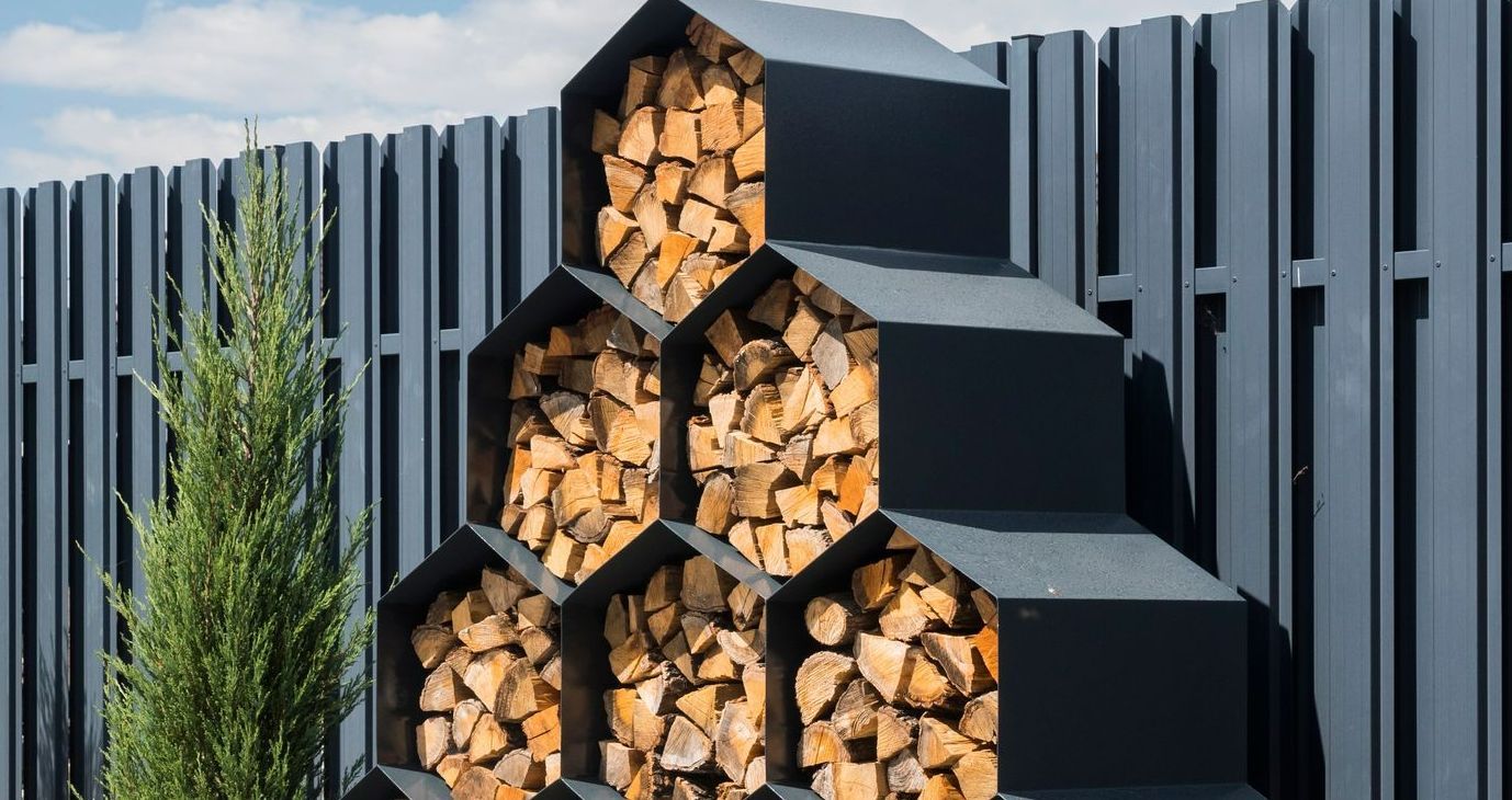 A Pile of Wood is Stacked on Top of Each Other in Front of a Fence — Stockers & Partridge In Raymond Terrace, NSW