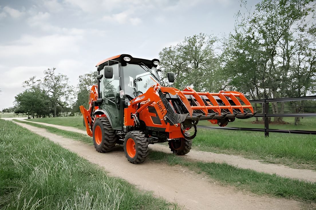A small orange tractor is driving down a dirt road.
